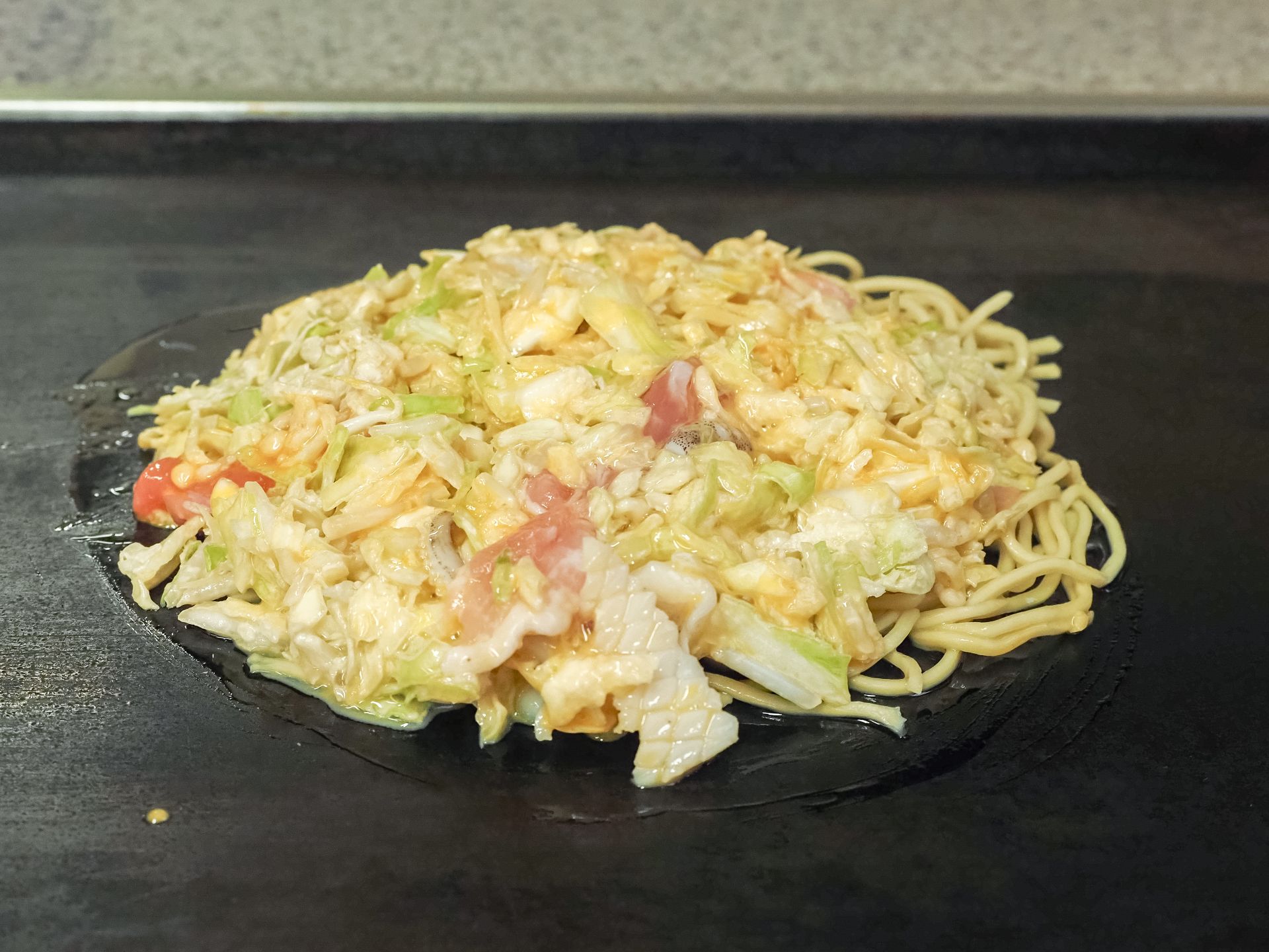 鉄板で焼かれるお好み焼き